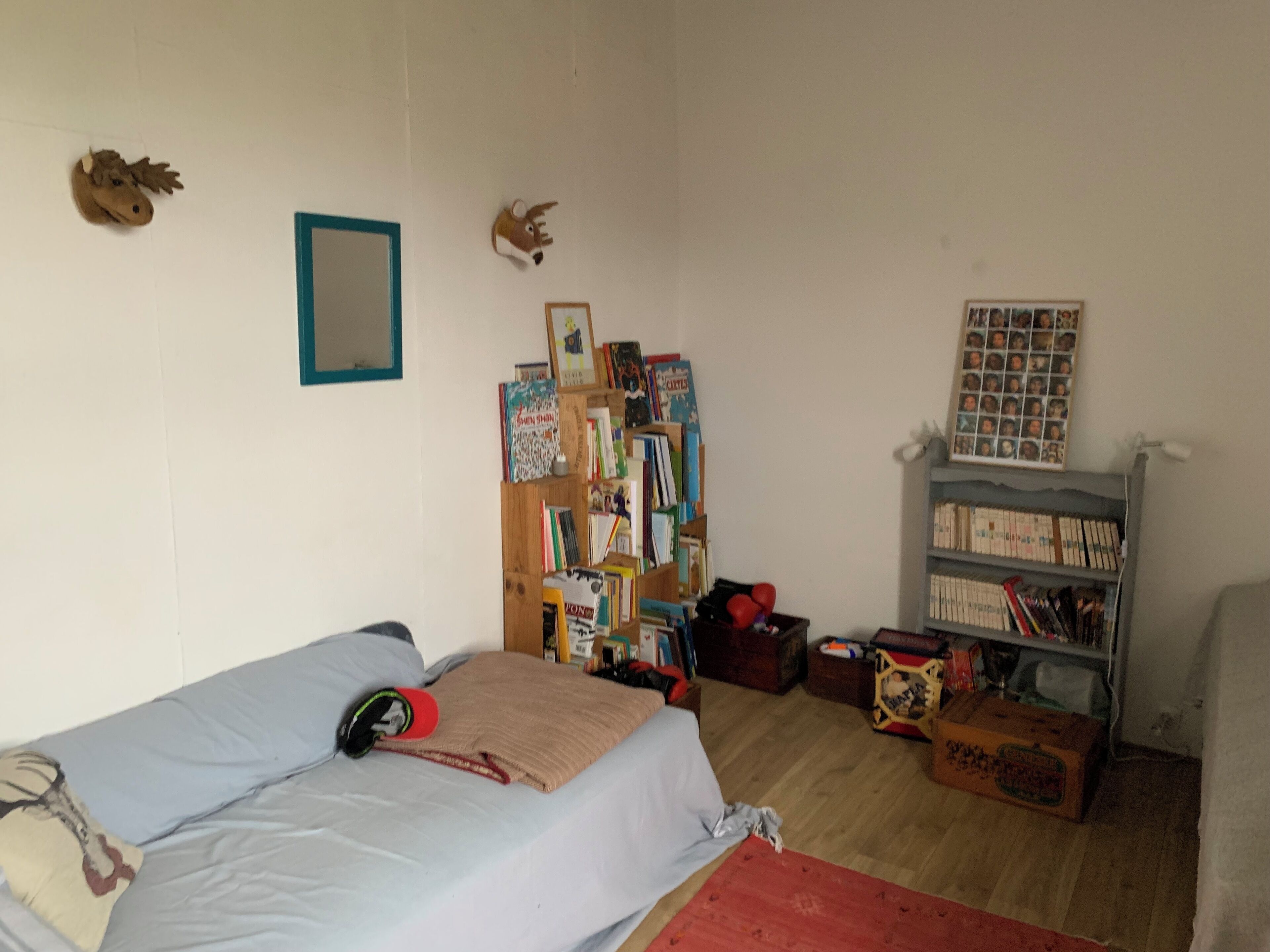 Une chambre à coucher avec un lit, une bibliothèque et un miroir fixé au mur.