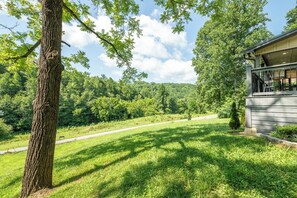 A cabin with a porch, surrounded by a grassy area and trees. - 🦌 Wildlife Cove, Wooded Family Cabin with Arcade Game Room, Sleeps 12 (Sevierville)