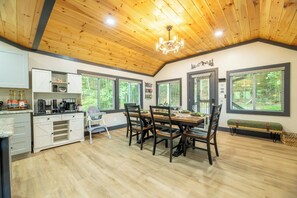 A spacious kitchen with a dining area, wooden ceiling, and large windows. - 🦌 Wildlife Cove, Wooded Family Cabin with Arcade Game Room, Sleeps 12 (Sevierville)