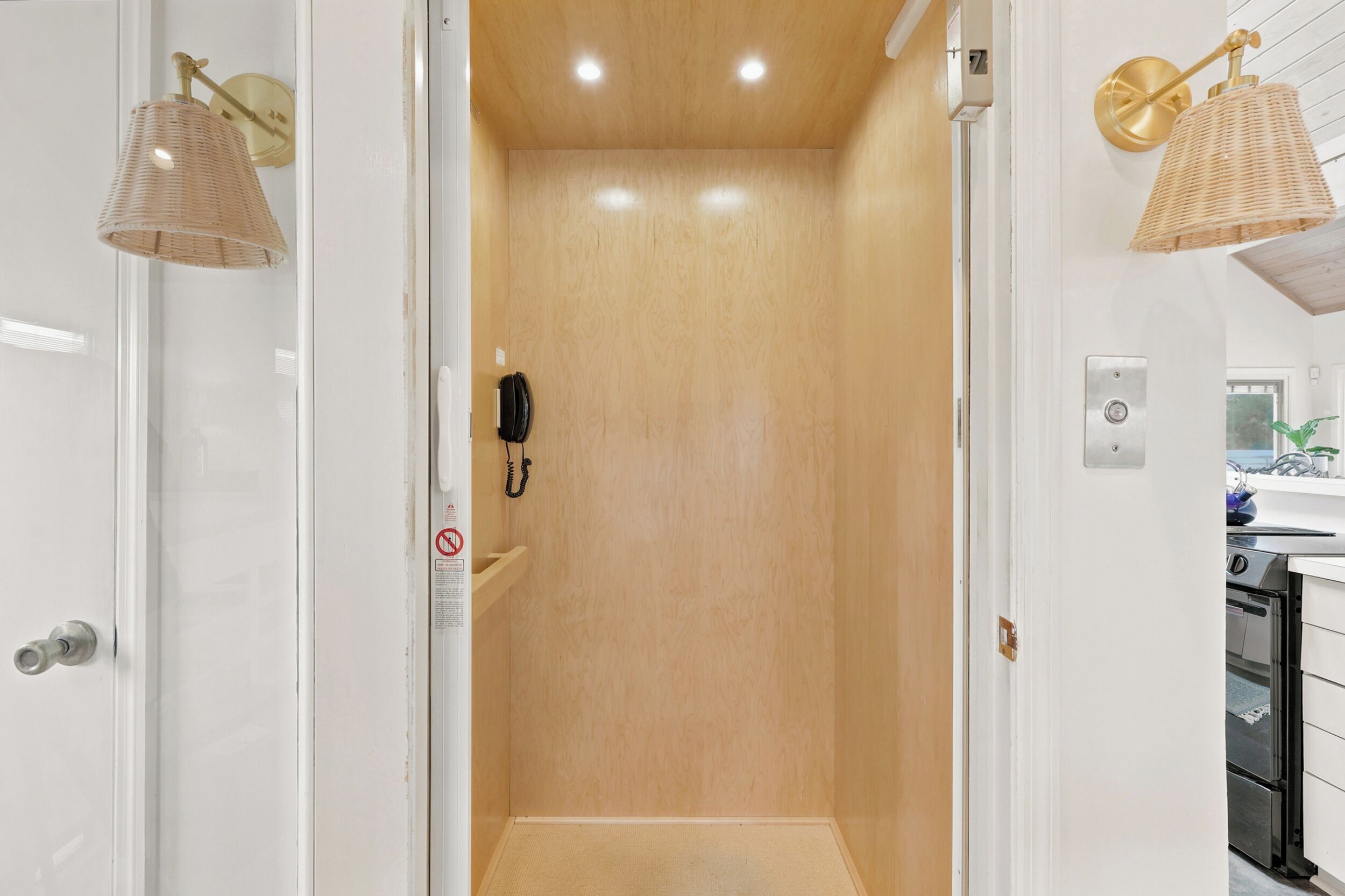 A bathroom with a wooden door, a telephone, and a wall-mounted light fixture.
