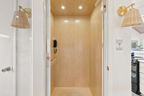 A bathroom with a wooden door, a telephone, and a wall-mounted light fixture. - Steps from the ocean in Debordieu (Georgetown)