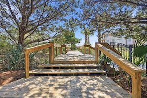 A wooden staircase leading up to a building, surrounded by trees and greenery.