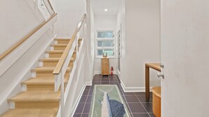 A staircase with wooden steps and white railings, a small wooden cabinet, and a fire extinguisher. - Steps from the ocean in Debordieu (Georgetown)