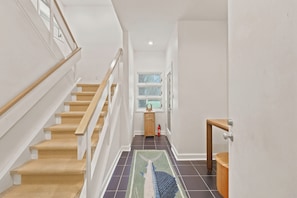 A staircase with wooden steps and white railings, a small wooden cabinet, and a fire extinguisher.