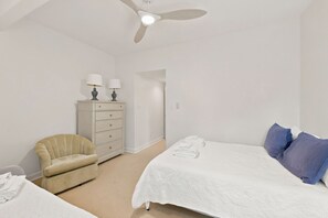 A bedroom with a bed, a chair, a dresser, a ceiling fan, and a door. - Steps from the ocean in Debordieu (Georgetown)