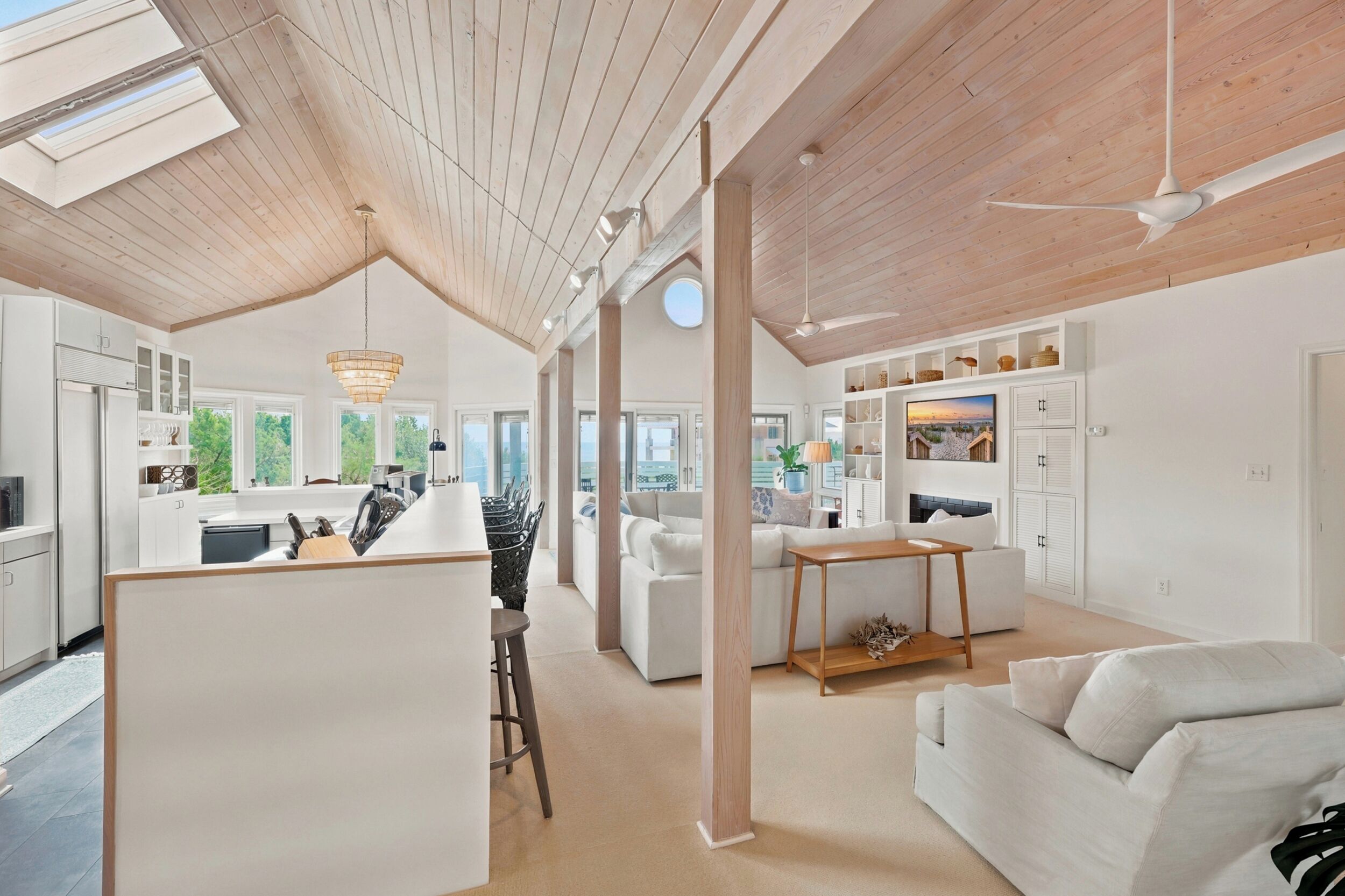 A spacious living area with a high ceiling, a kitchen with modern appliances, and a dining area with a round table.