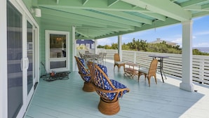 A covered outdoor deck with seating and a table, overlooking a scenic view. - Steps from the ocean in Debordieu (Georgetown)