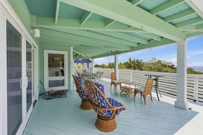 A covered outdoor deck with seating and a table, overlooking a scenic view.