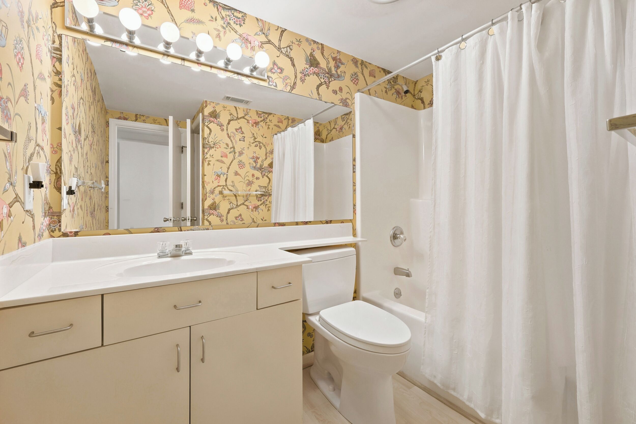 A bathroom with a vanity, a toilet, and a shower curtain.