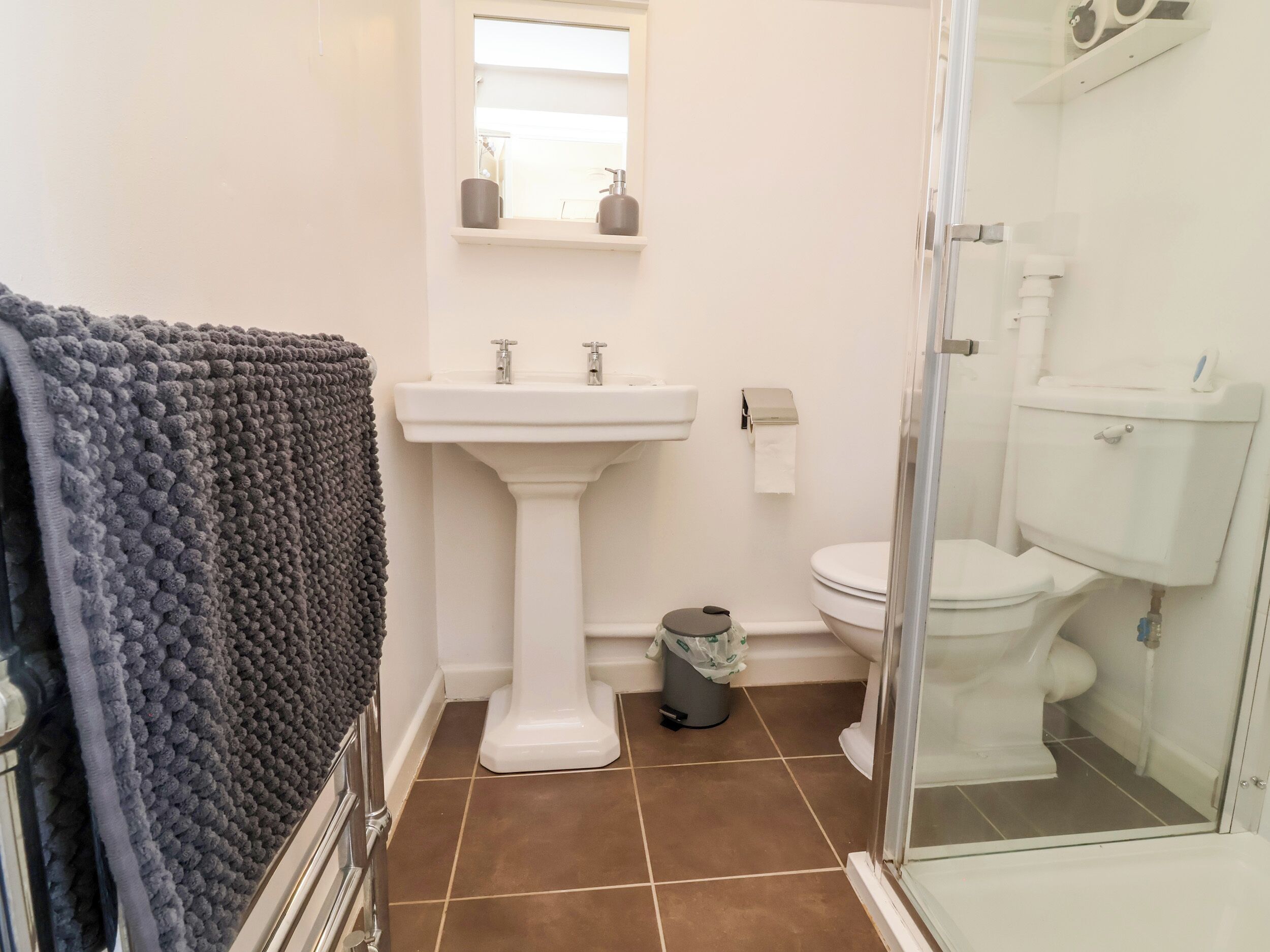 Un bagno con lavabo a piedistallo, water e doccia.