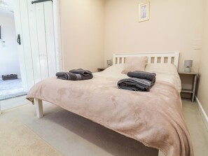 A neatly made bed with folded towels, a bedside lamp, and a framed picture on the wall. - Coach House (Beaworthy)