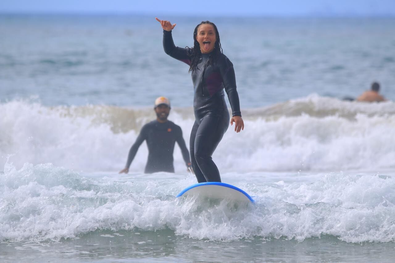 Una persona surfeando una ola con una tabla de surf azul.