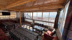 A room with a high ceiling, large windows, a sofa set, a coffee table, and a television. - surfcaptain (Tamraght)