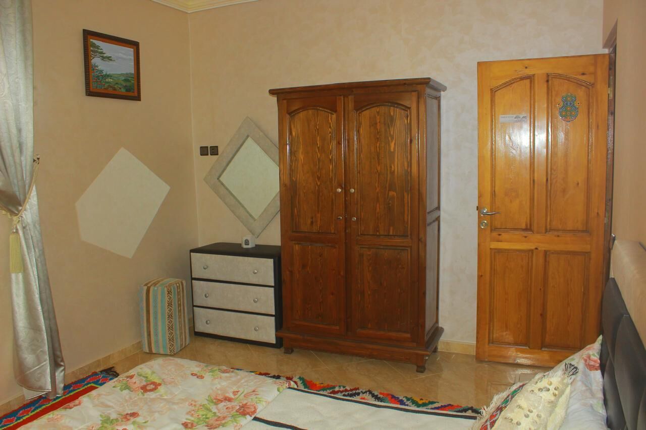 Une chambre à coucher comprenant un lit, une armoire, une commode, un miroir et une porte.