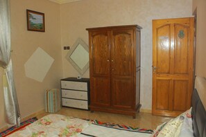 Un dormitorio con cama, armario, cómoda, espejo y puerta.