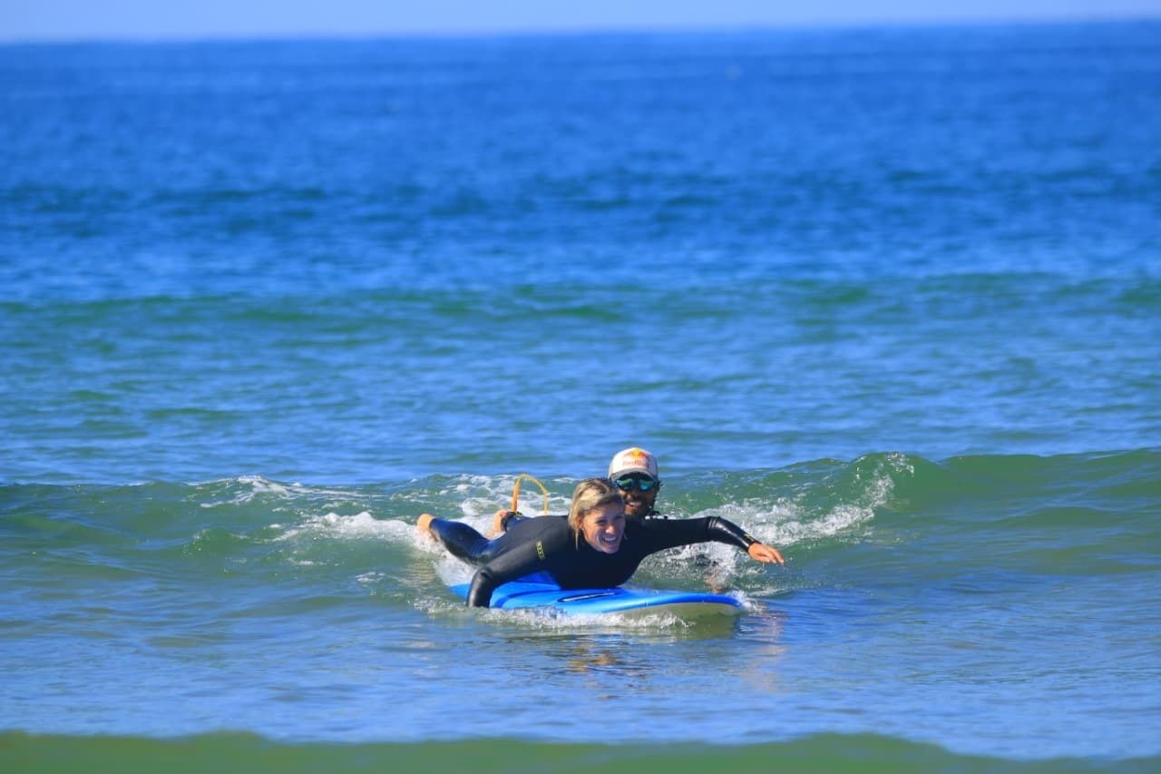 En person på et blåt surfbræt i havet.
