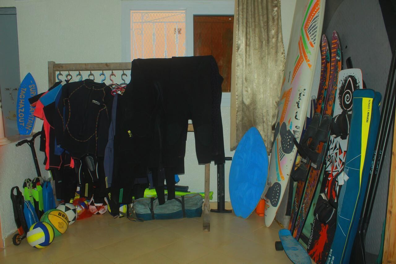 Una habitación con tablas de surf, trajes de neopreno y pelotas de playa.