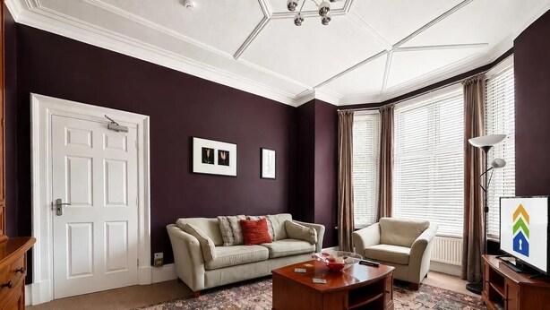 Una sala de estar con sofá, sillón, mesa de centro y televisor.