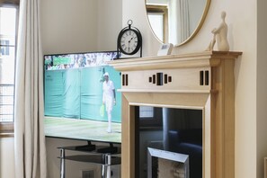 A television displaying a tennis match, a fireplace, and a wall-mounted clock. - Beautiful 4BR Home in Peaceful Area | Lots Around - Pass the Keys (Belfast)