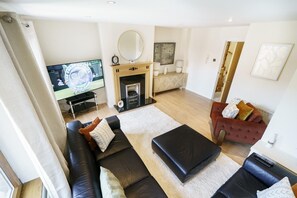 A modern living room with a fireplace, a television, and a red sofa. - Beautiful 4BR Home in Peaceful Area | Lots Around - Pass the Keys (Belfast)