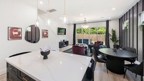 Una cucina moderna con isola in marmo, luci a sospensione e zona pranzo con un tavolo rotondo e sedie.