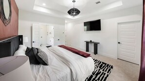 Una camera da letto moderna con un letto, comodini, una TV e un grande specchio.