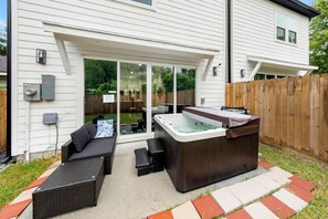 Eine Außenpatio mit Whirlpool, Sitzgelegenheit und Holzzaun.