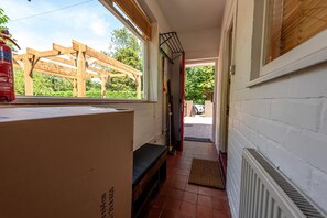 A narrow hallway with a wooden pergola outside, a fire extinguisher, and a radiator inside.