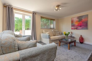 A living room with a sofa, armchairs, a coffee table, and a painting on the wall.