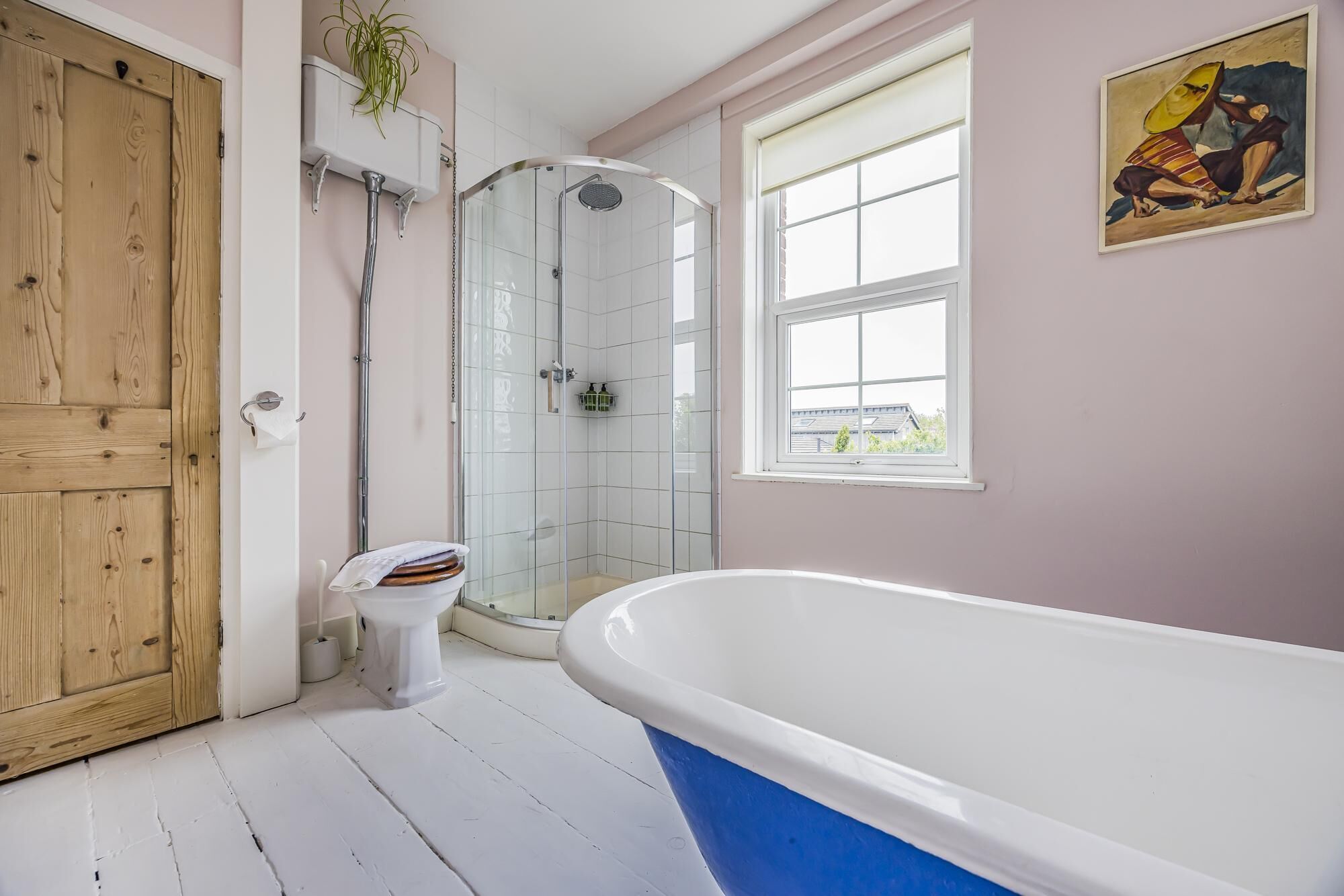 Et badeværelse med badekar, brusebad, toilet og en trædør.