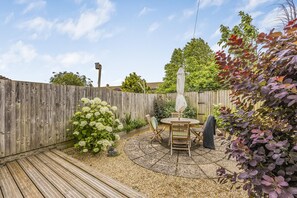 Eine Holzterrasse mit einer Sitzgruppe in Kreisform und einem Holzzaun im Hintergrund.
