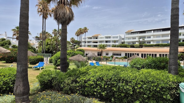 Ein Resort mit Schwimmbad, Liegestühlen und Palmen.