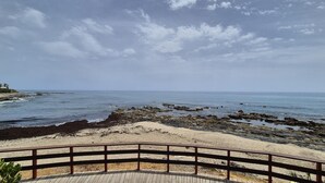 A coastal view with a wooden deck and rocky shoreline. - Beachfront Escape in Miraflores - Pass the Keys (Las Lagunas de Mijas)