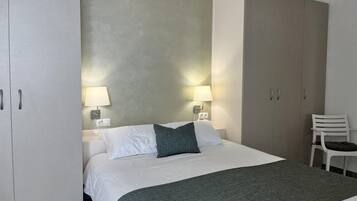 Ein Hotelzimmer mit einem Bett, zwei Nachttischen mit Lampen, einem Sessel und einem Kleiderschrank.