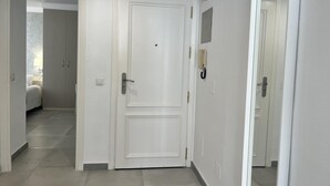 A hallway with a white door, a light switch, and a wall-mounted intercom. - Beachfront Escape in Miraflores - Pass the Keys (Las Lagunas de Mijas)