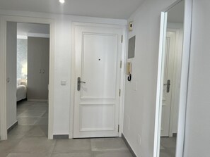 Ein Flur mit einer weißen Tür, einem Lichtschalter und einem an der Wand montierten Gegensprechanlage.