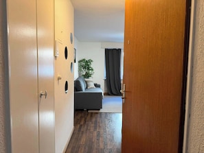 Un pasillo que conduce a una sala de estar con un sofá, una planta y una puerta con un número.