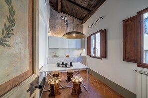 A kitchen with a white countertop, a hanging pendant light, and a window with wooden shutters. - Casa Magnoli by MMega (Firenze)