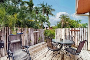 Eine Terrassengruppe im Freien mit Holzdeck, Metallstühlen, einem runden Tisch und einer Bambus-Umzäunung.