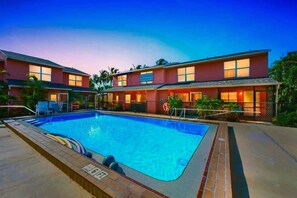 Ein Hotel mit Schwimmbad, mehreren Gästezimmern und einem umzäunten Außenbereich.