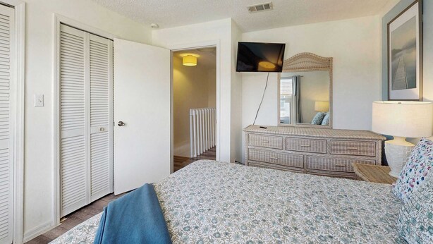 Un dormitorio con cama, cómoda, espejo y televisor.