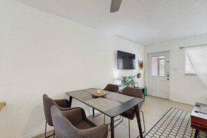 Ein Essbereich mit Tisch und Stühlen, einem an der Wand montierten Flachbildfernseher und einer Tür mit Fenster.