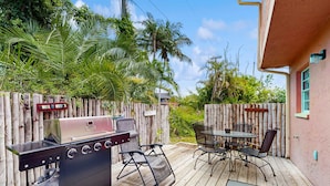 Un patio al aire libre con una parrilla de carbón, asientos y una terraza de madera.