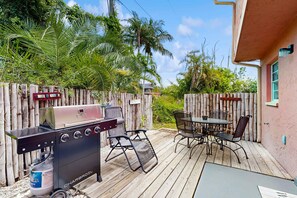 Eine Terrasse im Freien mit Holzboden, einer Holzkohlegrill und Sitzgelegenheiten.