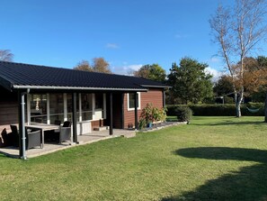 A house with a covered patio, a lawn, and trees. - Holiday Near Beach and Coastal Nature (Gørlev)