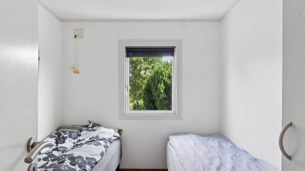 Un alojamiento pequeño y de una sola habitación con dos camas, ventana con vistas a zonas verdes y un espacio sencillo y despejado.