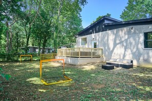 Una casa con terraza, estructura de juegos y sofá.