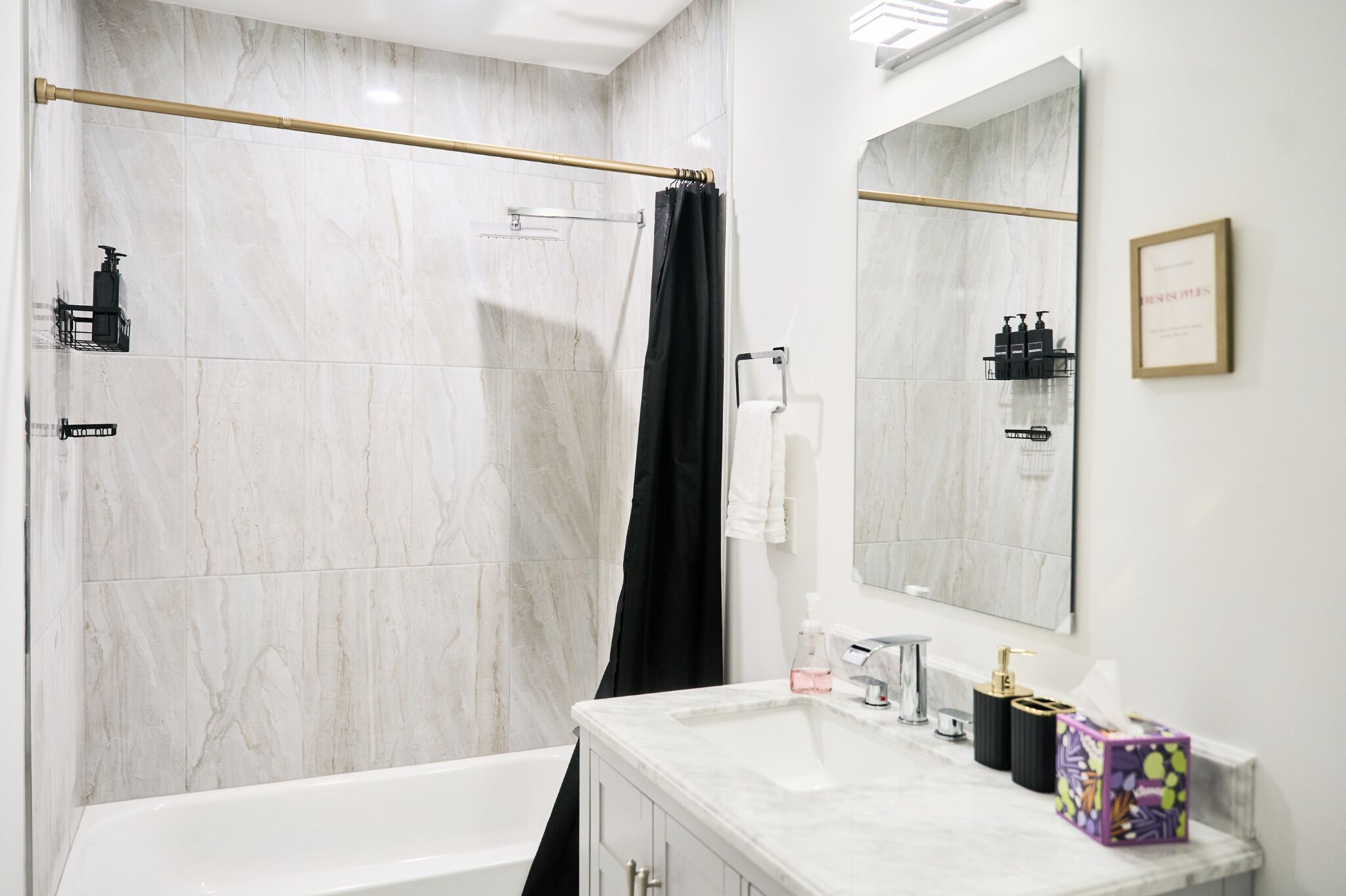Un baño moderno con ducha, bañera, tocador con espejo y artículos de aseo.