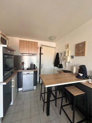Eine kleine Küche mit Geschirrspüler, Backofen, Mikrowelle und Holzschränken.
