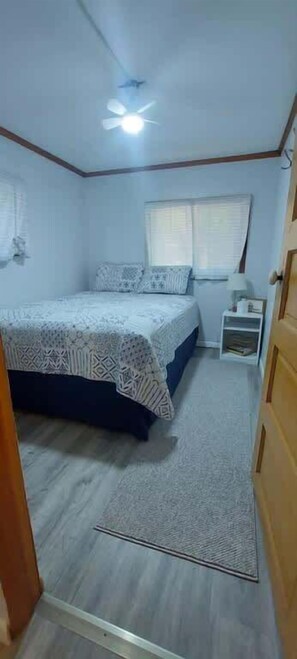 Ein Schlafzimmer mit Bett, Nachttisch, Deckenventilator.